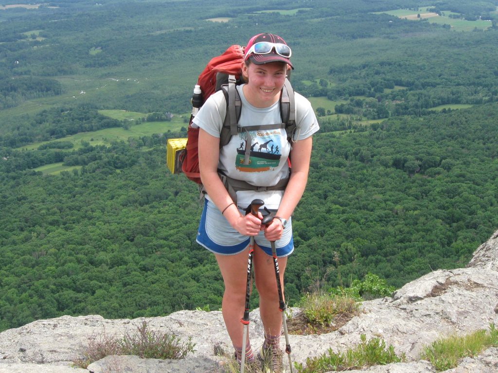 Woman standing on a cliff with a backpack
