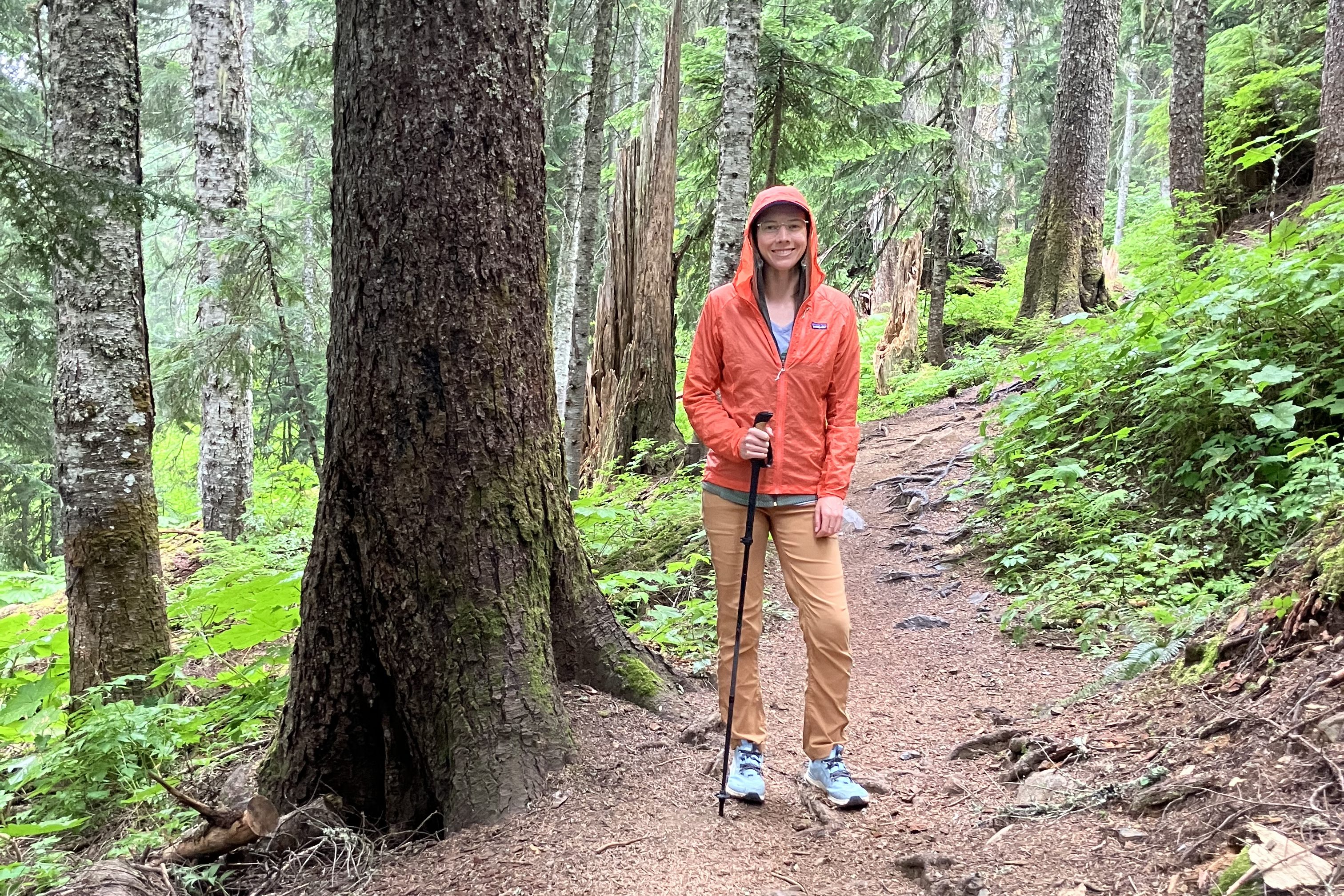 hiker in an orange windbreaker in the forest