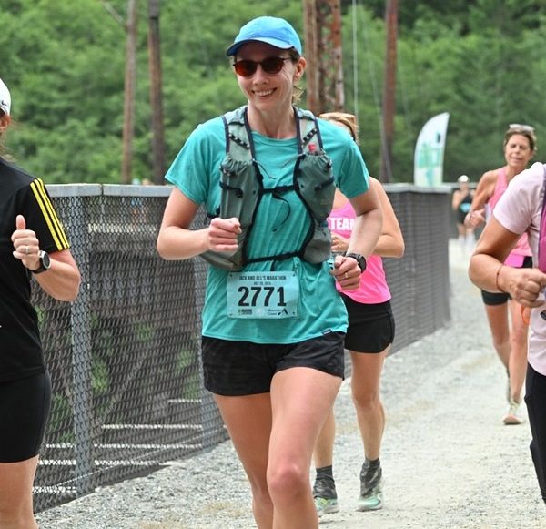 woman running with a running vest and bib