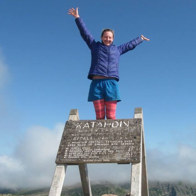 woman standing on a sign that says "Katahdin"